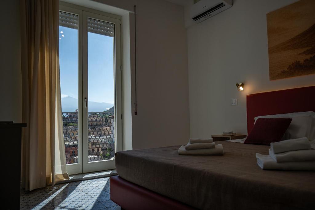 a bedroom with a bed and a large window at Light View in Taormina