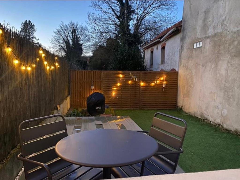 a patio with a table and chairs and a fence at Appartement avec jardin privé à 10 min de Disneyland, idéal familles in Couilly-Pont-aux-Dames