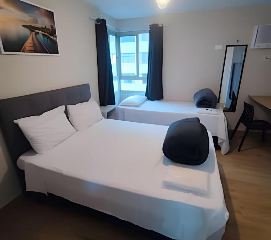 a room with two beds and a chair in it at Flat GoodLar Liberdade SP Hakka Eventos in Sao Paulo