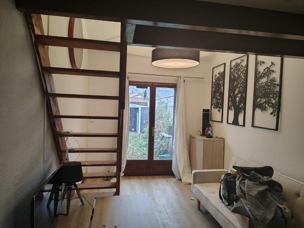 a living room with a staircase and a couch at Studio avec chambre au calme face à un champs in Castelginest