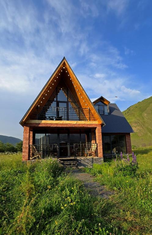 a house with a thatched roof on top of a field at Grand Mountain Cottage in Kazbegi