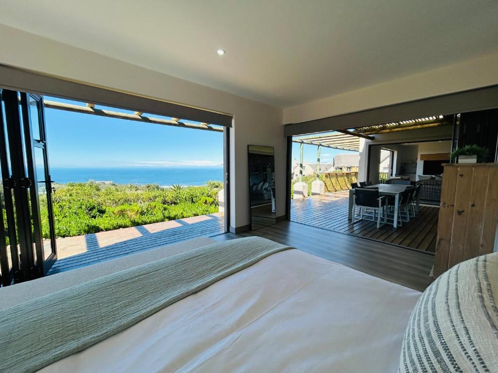 a bedroom with a bed and a view of the ocean at Bayview Bliss at Springerbaai Luxury Eco Villa with Ocean Views & Beach Access in Mossel Bay