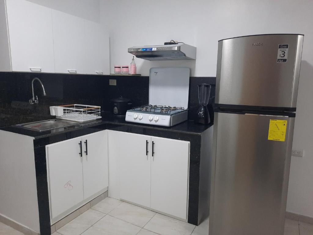 a kitchen with a stainless steel refrigerator and white cabinets at MiniSuite in Machala