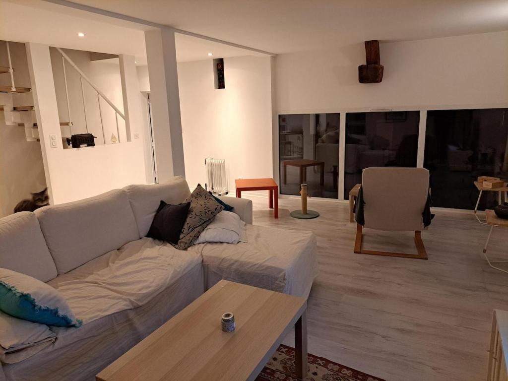 ein Wohnzimmer mit einer weißen Couch und einem Tisch in der Unterkunft Peaceful house just for you! in La Ville-du-Bois