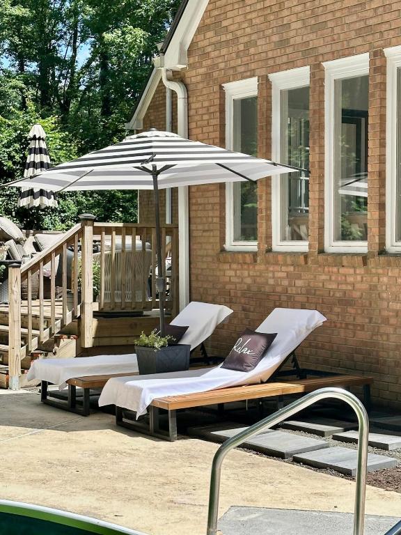 スネルビルにあるCamellias Haven Cozy New Reno 2Bed Apt 40 Min to ATLのラウンジチェア2脚、プールサイドのパラソル1本