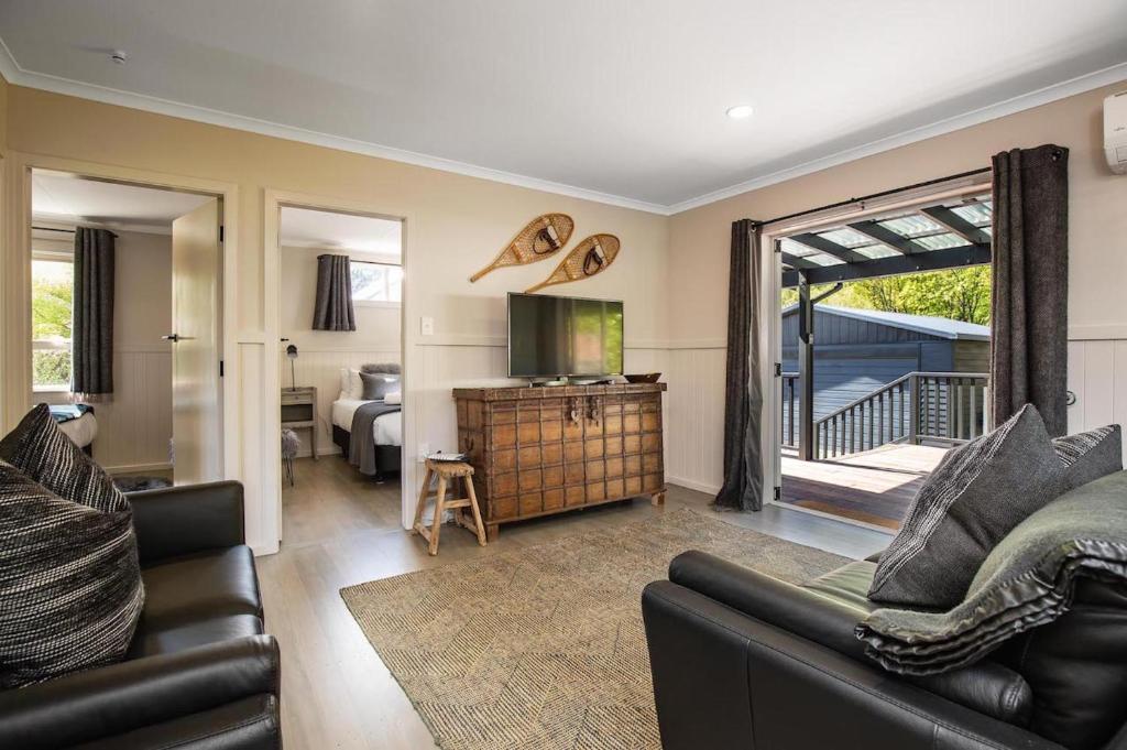 a living room with a couch and a television at Cartvale - 3 bed cottage in historic Arrowtown in Arrowtown