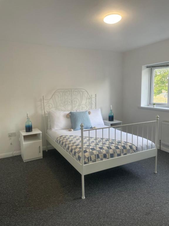 ein Schlafzimmer mit einem weißen Bett mit blauen Kissen in der Unterkunft 4 Bed Family & Work Ready Home in Ponders End