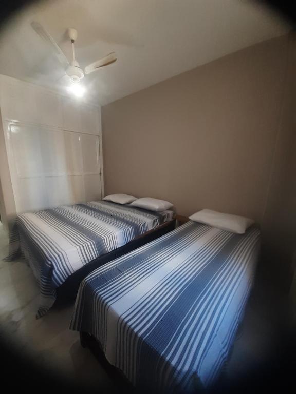 two beds in a small room with a ceiling at castanheiras perto de tudo,com cadeiras e guarda sol in Guarapari