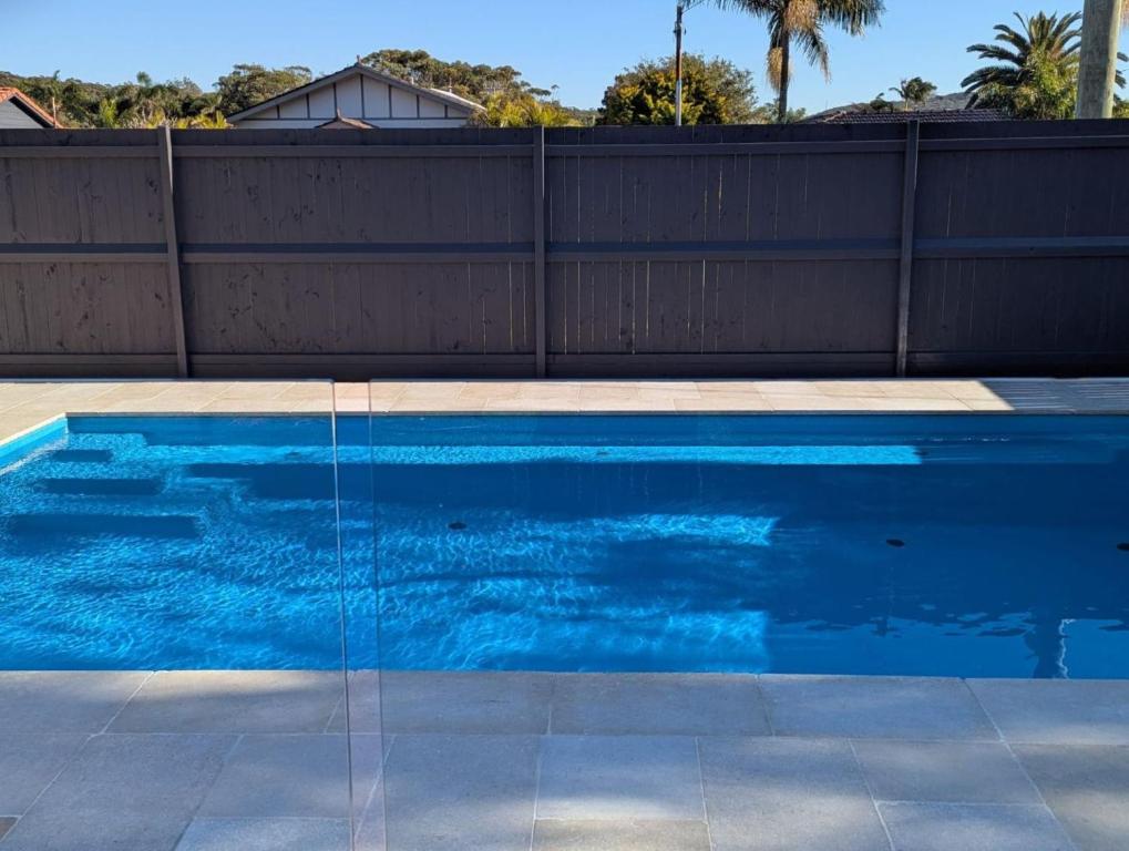 a blue swimming pool in front of a fence at Blue Fish 41 Boulder Bay Road in Fingal Bay