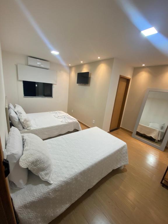 Una habitación de hotel con dos camas y un televisor. en Bik House Pousada e Festa, en Mimoso do Sul