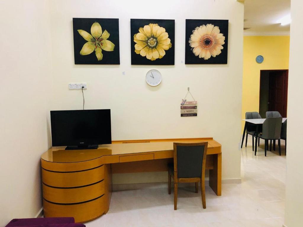 a room with a desk with a tv and flowers on the wall at Homestay Salam Marang Terengganu in Marang
