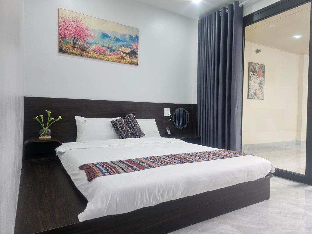 a bedroom with a large bed and a painting on the wall at The Dang's Home in Lao Cai in Pho Mới
