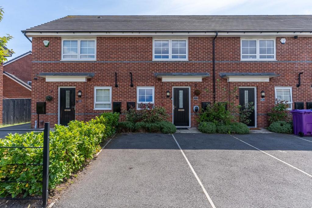 a red brick house with a parking lot at Walk To Airport - 3 Bedrooms x2 Driveway - EV Charging - Washer & Dryer in Liverpool