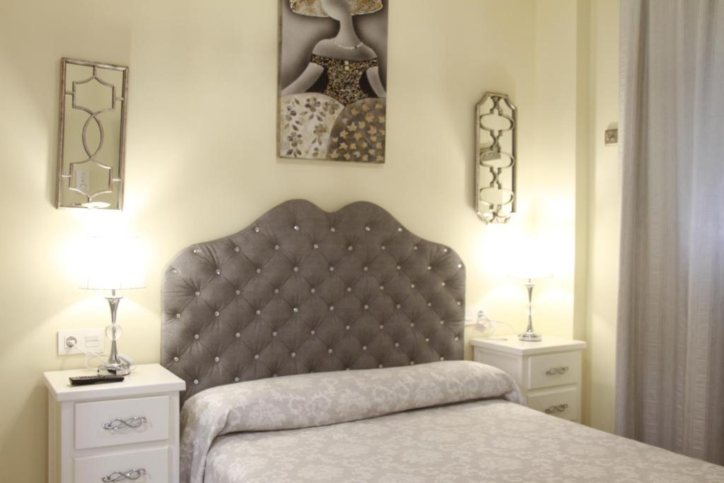コニル・デ・ラ・フロンテーラにあるHostal Flor De Lis- Lojoのベッドルーム1室(ベッド1台、ナイトスタンド2台、ランプ2つ付)