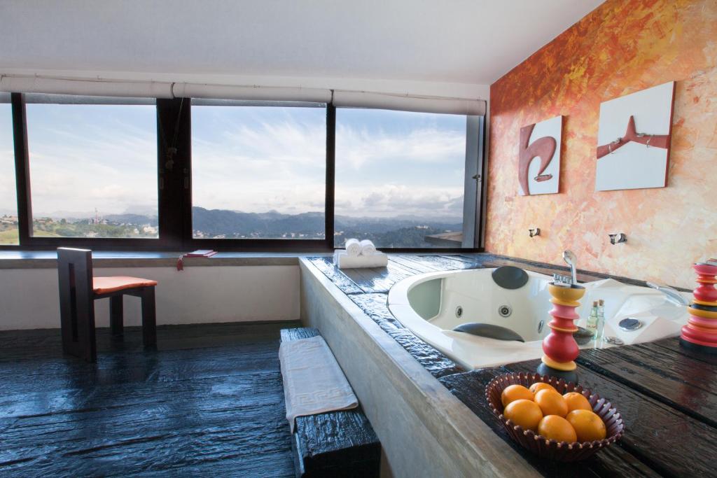a bathroom with a tub and a sink with windows at The Theva Residency in Kandy