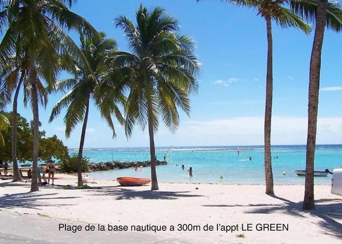 a beach with palm trees and people in the water at Madikera Resort Beach Near in Saint-François