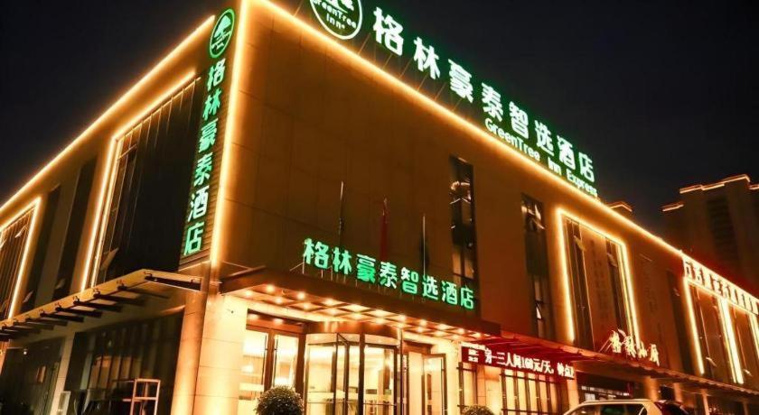 ein Gebäude mit Neonschildern an der Seite in der Unterkunft GreenTree Inn Express Datong High-Speed Railway Station Wanda Plaza Fangte in Shuiposhi