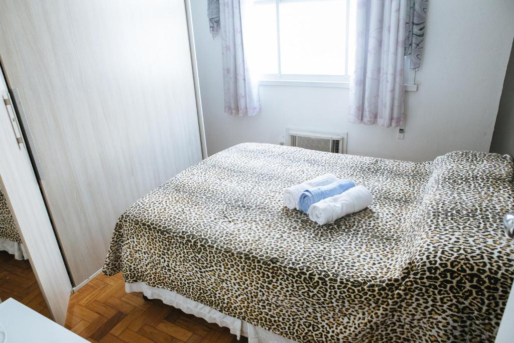 1 dormitorio con 1 cama con estampado de leopardo y 2 toallas en Felipe de Oliveira Apartment, en Río de Janeiro