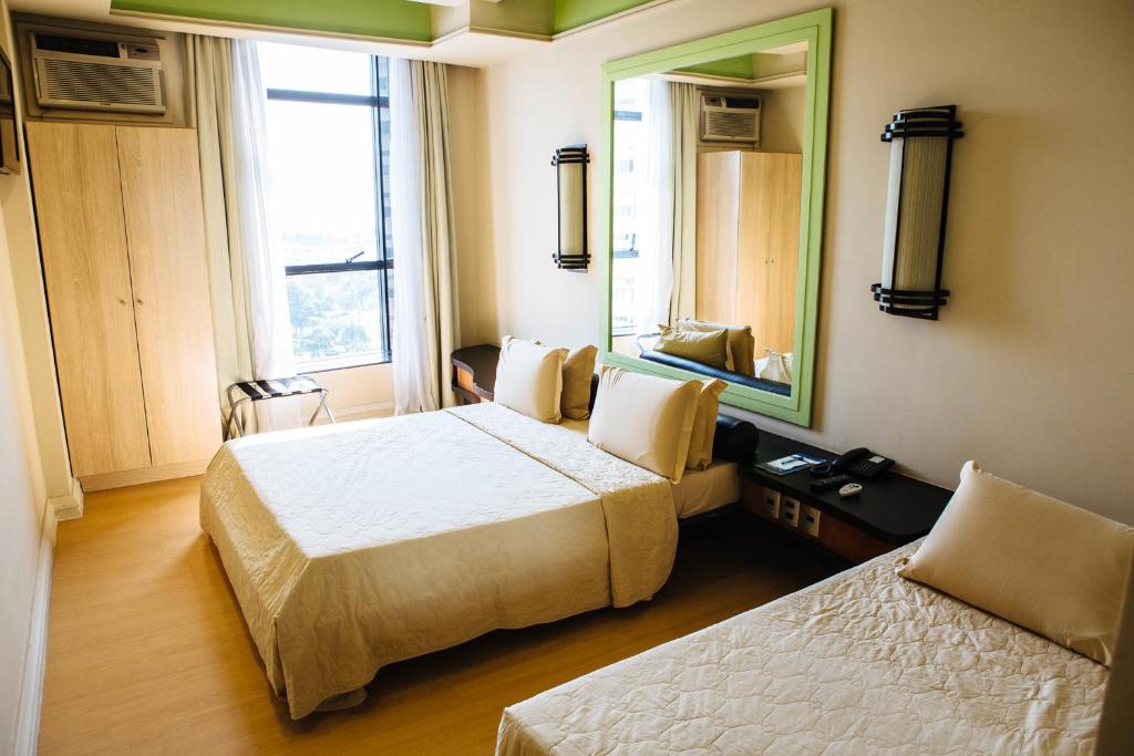 a hotel room with two beds and a mirror at Diamond Hotel in Rio de Janeiro