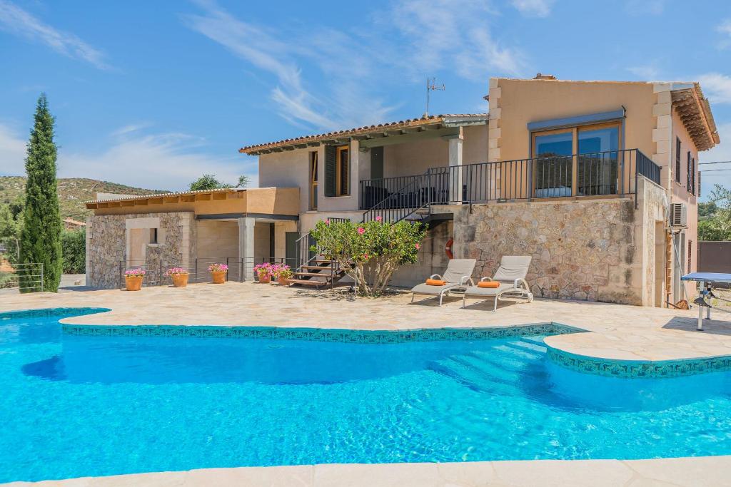 a villa with a swimming pool in front of a house at Garriga Vila in Pollença