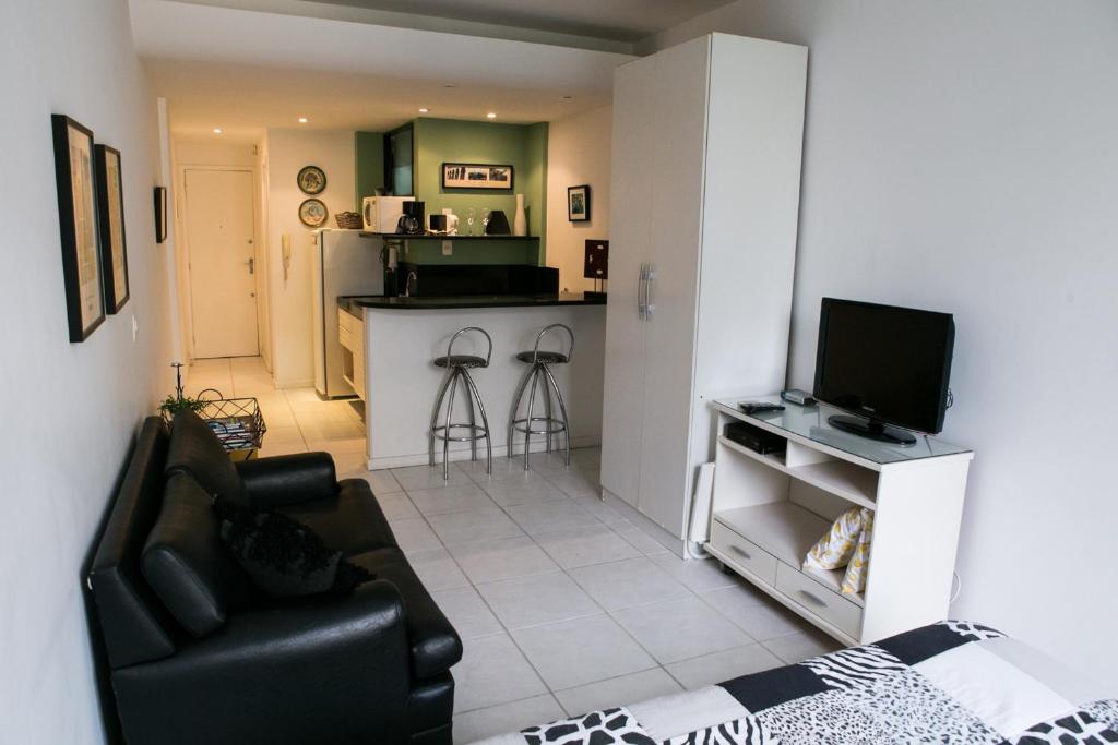 uma sala de estar com um sofá e uma televisão em Charmoso Flat em Ipanema no Rio de Janeiro