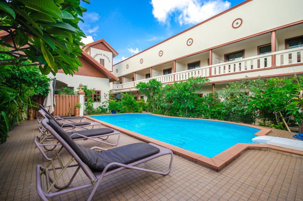 a swimming pool in front of a hotel with lounge chairs at Namphung Phuket Boutique Resort in Rawai Beach