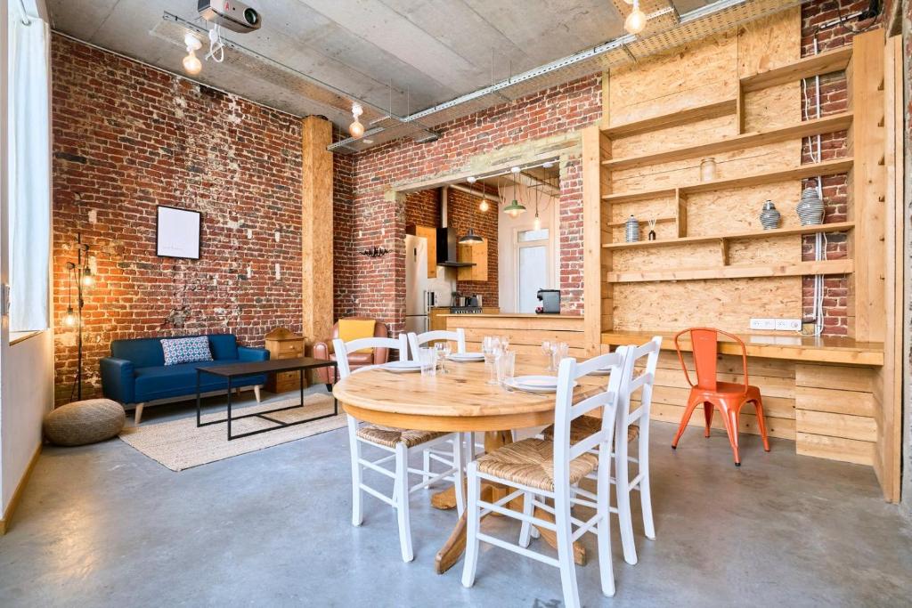une pièce avec une table et des chaises et un mur de briques dans l'établissement Appartement 2 chambres atypique en souplex, à Lille