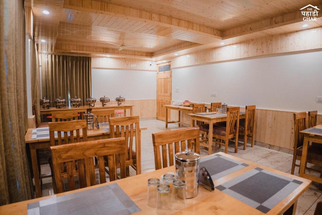 a dining room with wooden tables and chairs at the pahadi ghar in Gushaini