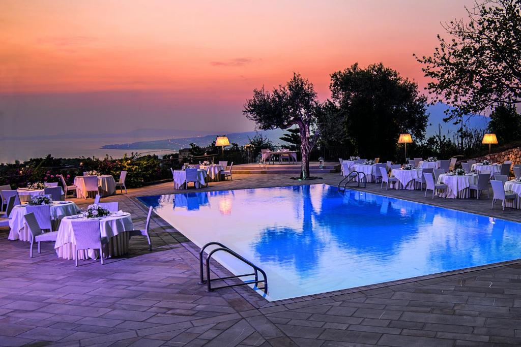 een zwembad met tafels en stoelen en een zonsondergang bij San Lorenzo - Hotel & SPA in Lettere