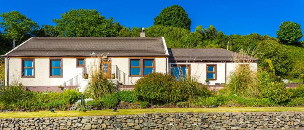 a white house with a gray roof and a stone wall at Cairnryan Bed and Breakfast in Cairnryan