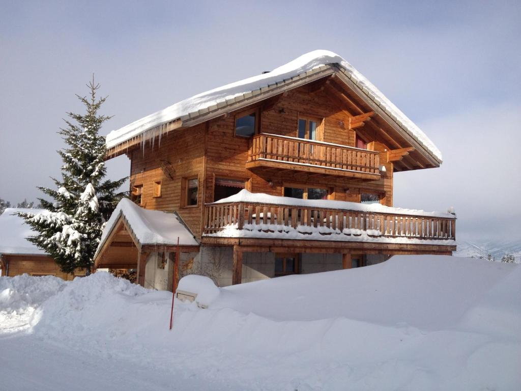 una cabaña de madera en la nieve con un patio cubierto de nieve en Chalet le Lagopède, en La Joue du Loup