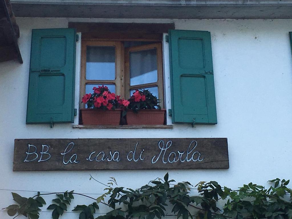 una ventana con persianas verdes y flores en un edificio en La Casa di Marla en Sirmione