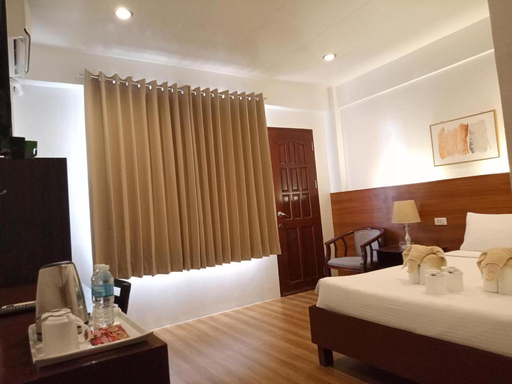 a hotel room with two beds and a chair and a window at Zosimo's Inn in Siquijor