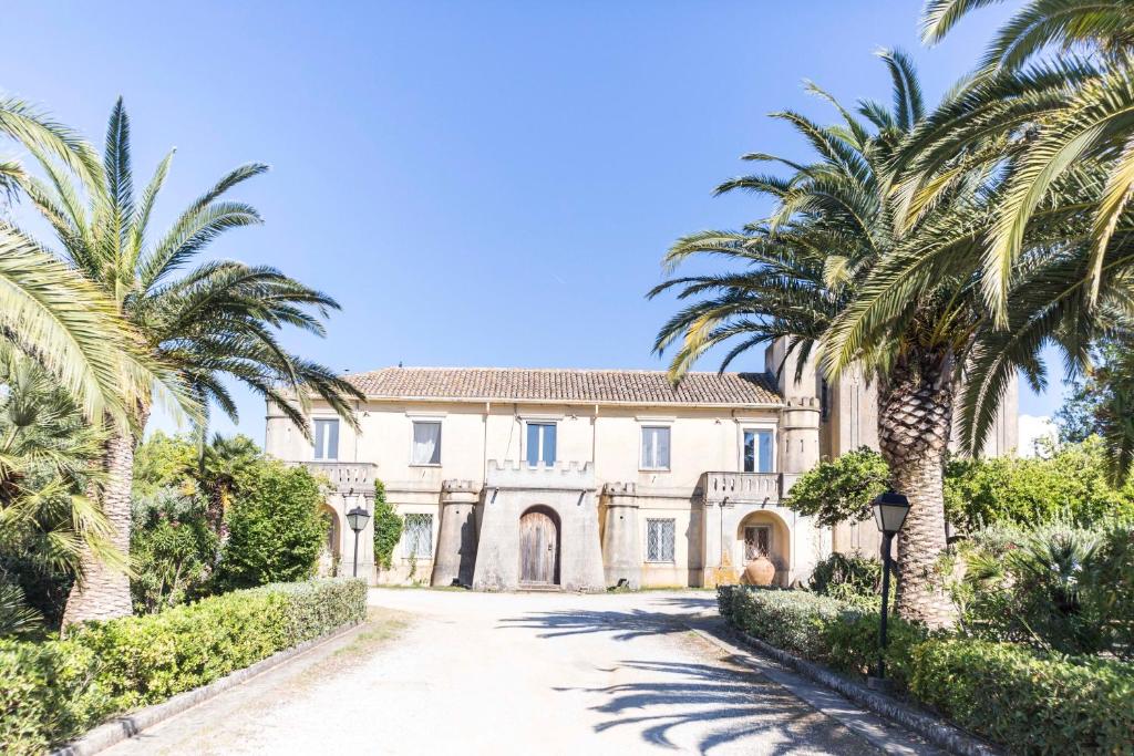 une maison avec des palmiers en face d'une allée. dans l'établissement Feudo di Villa Anticaglia, à Briatico