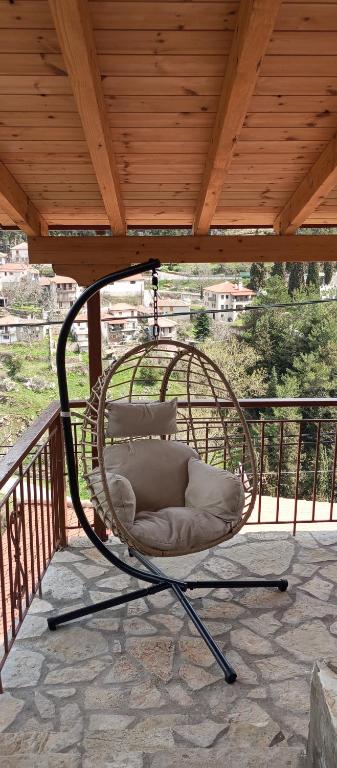 a hanging chair on a porch with a wooden roof at family home in Dhimitsana
