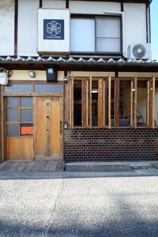 a building with wooden doors and a sign on it at 一棟貸し宿 ローカルプライド大和高田 in Yamatotakada