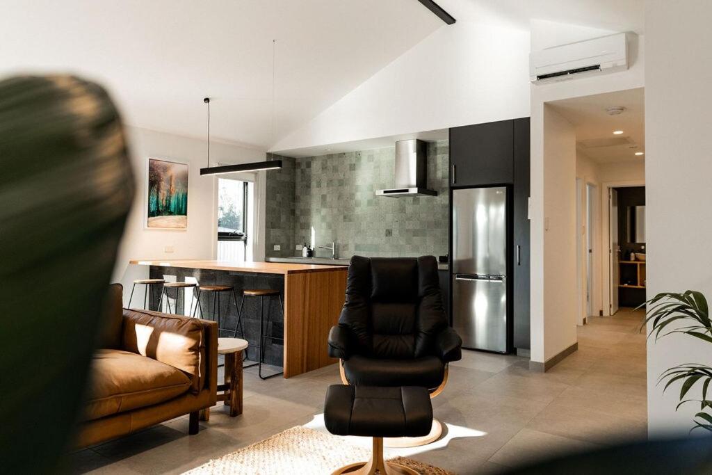 a living room with a couch chairs and a kitchen at Villa 2 - Greenstone Villas in St Helens