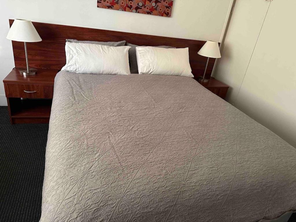 Un dormitorio con una cama con dos mesitas de noche y dos lámparas. en By the Harbour Gem, en Sídney