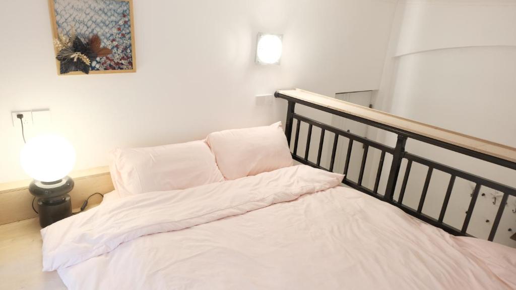 a bed with white sheets and pillows in a room at FFC sweet home on Shaanxi Road in Shanghai