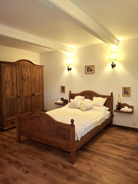 a bedroom with a large wooden bed with white sheets at Białowieska Przystań in Białowieża