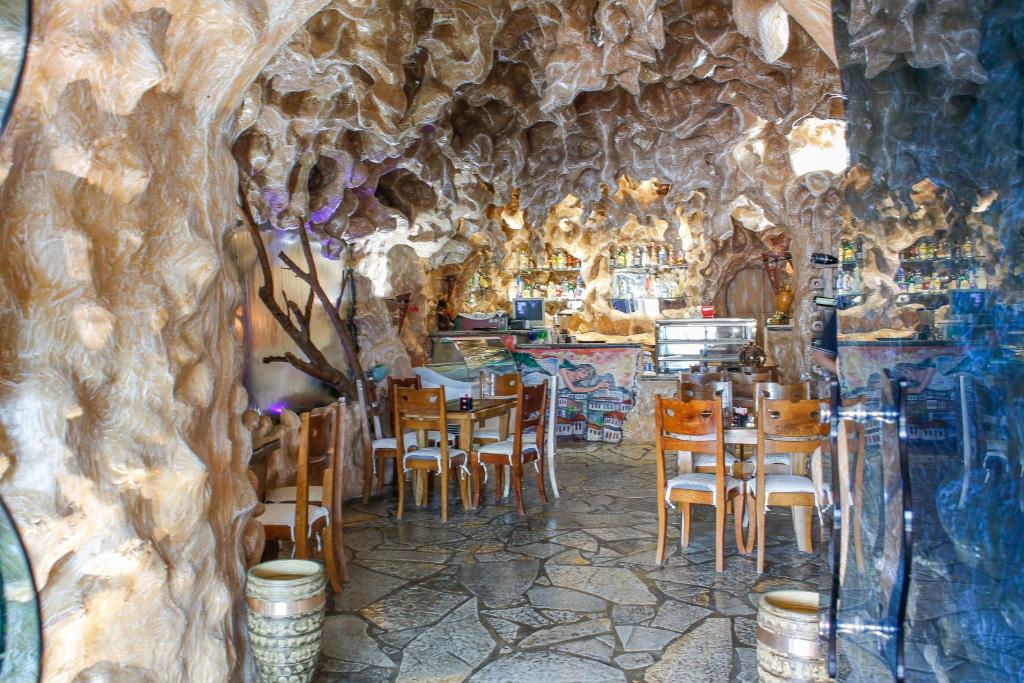 a restaurant with tables and chairs in a cave at Hotel Shpella in Berat