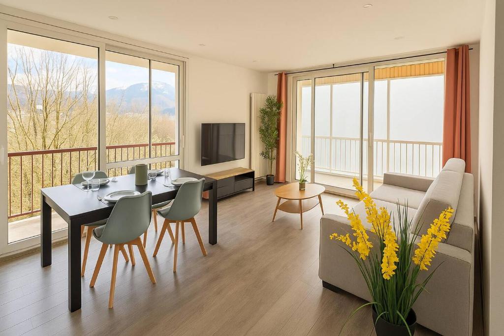 un salon avec une table, des chaises et une télévision dans l'établissement Spacious And Quiet Apartment, à Meythet