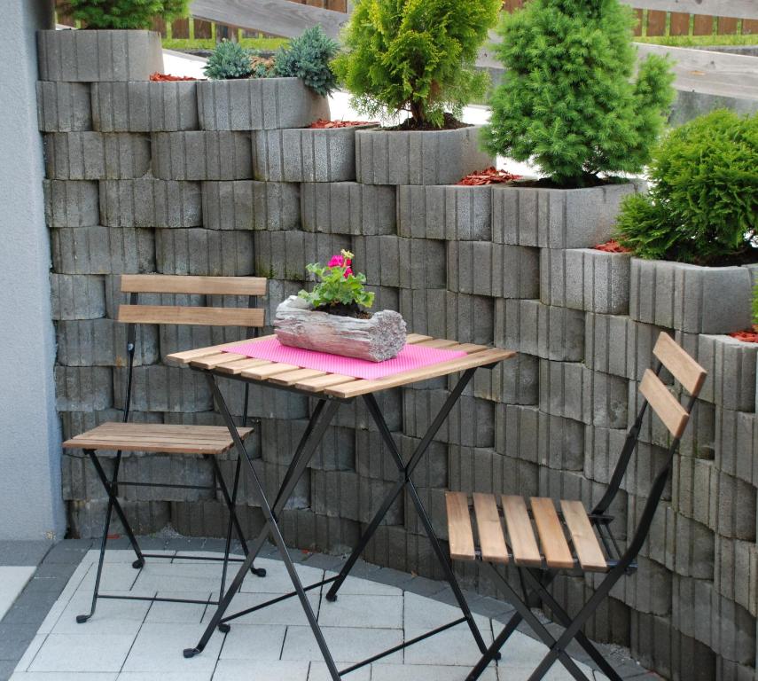 a table and chairs on a patio with a retaining wall at Ferienwohnung Kendler in Hüttschlag