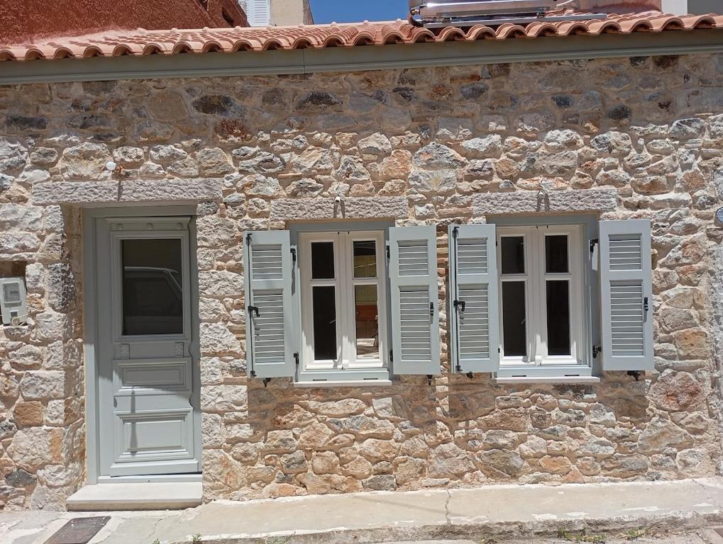 a stone building with two windows and white shutters at Casa dell'Arte Nafplio in Nafplio