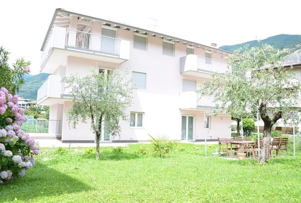 a large white building with a picnic table in a yard at Appartamenti Laly in Arco