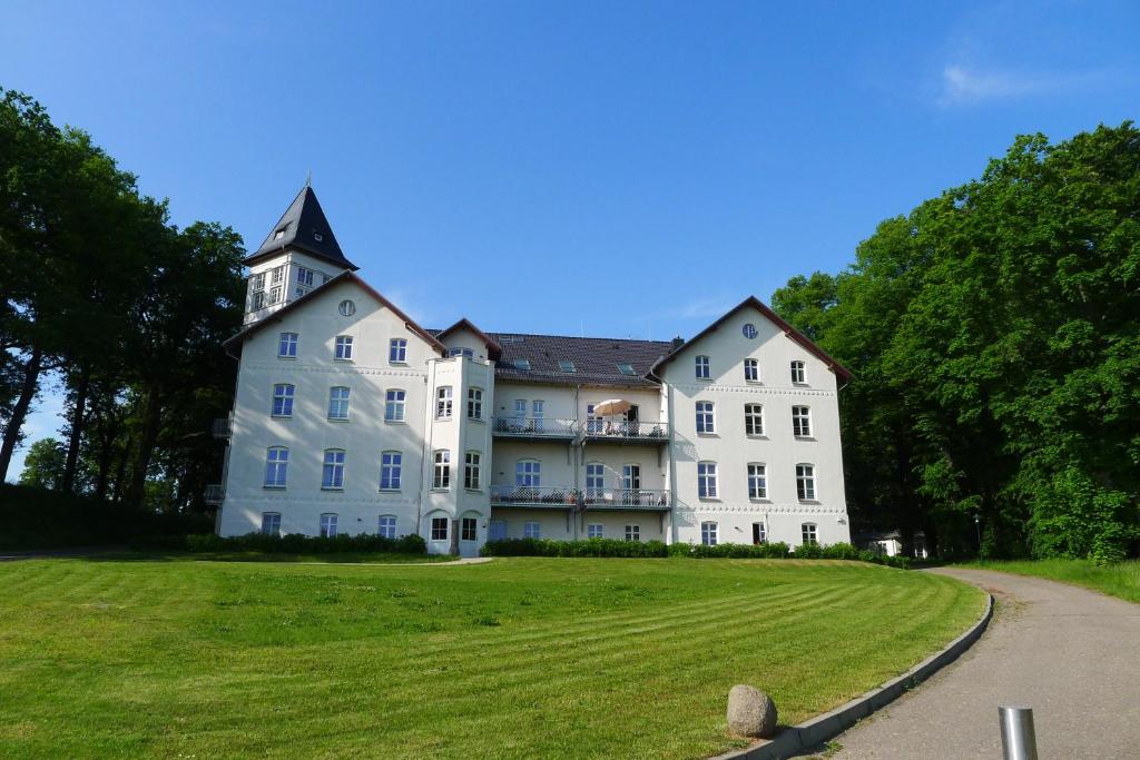 ein großes weißes Haus mit einem Uhrturm oben in der Unterkunft Jadgschloss zu Hohen Niendorf in Hohen Niendorf