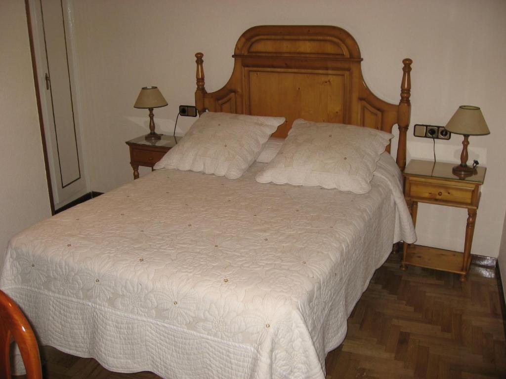 a bedroom with a large bed with white sheets and two lamps at Hostal Maria Cristina in Madrid