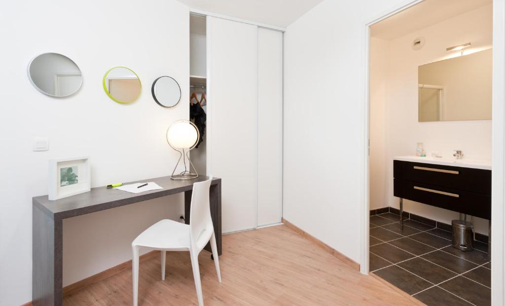 a bathroom with a desk and a mirror at Ténéo Apparthotel Talence Arthena in Talence