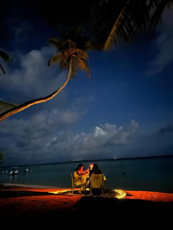 two people sitting at a table on the beach at night at Nika Inn Himandhoo in Himandhoo 