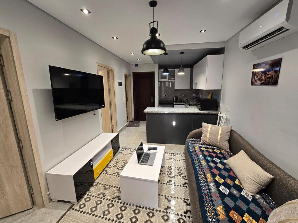 a living room with a couch and a flat screen tv at Luxury chalet in Porto Golf for rent in El Alamein